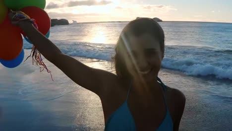 Happy-woman-holding-balloons-at-beach