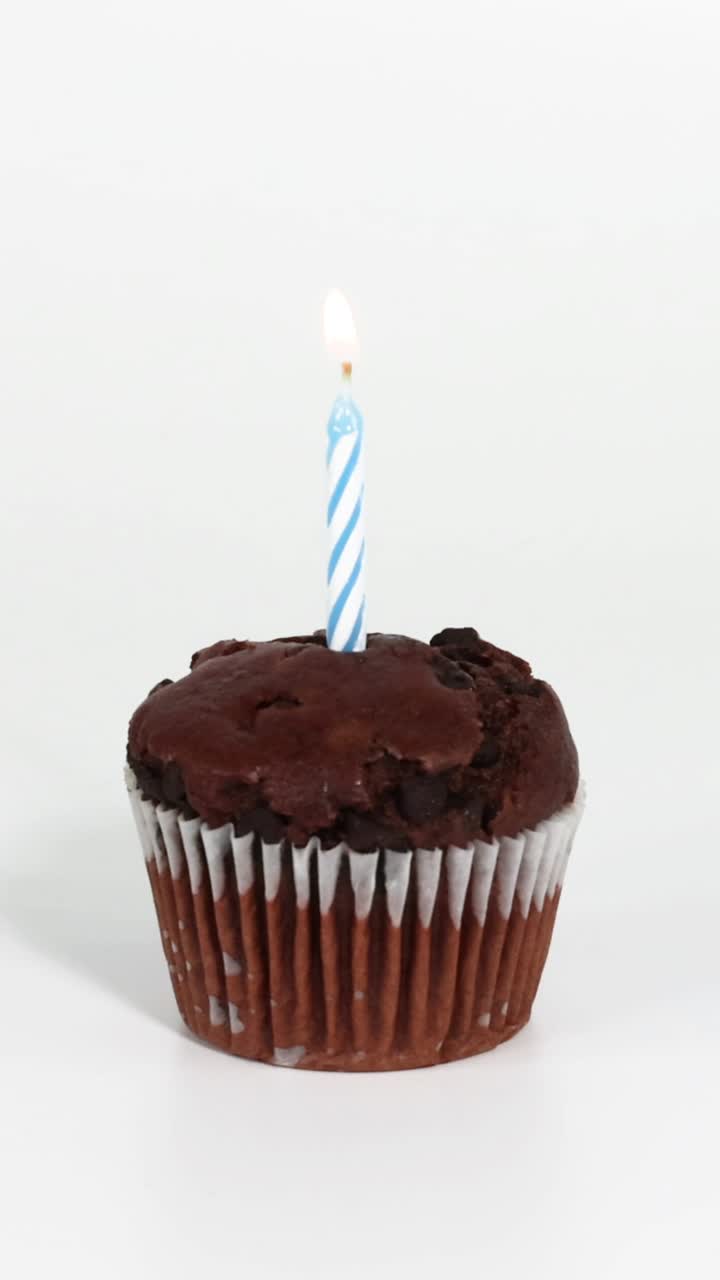 Una mano accende una candela su un cupcake al cioccolato