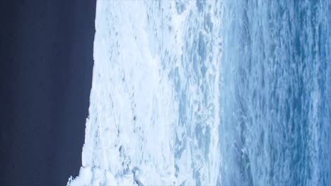 waves rolling in slow motion onto a black sand beach