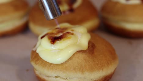 crop cook burning cream on dessert with gas burner in bakery