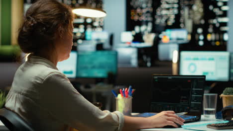 business professional studies candlestick charts and forex data in office late