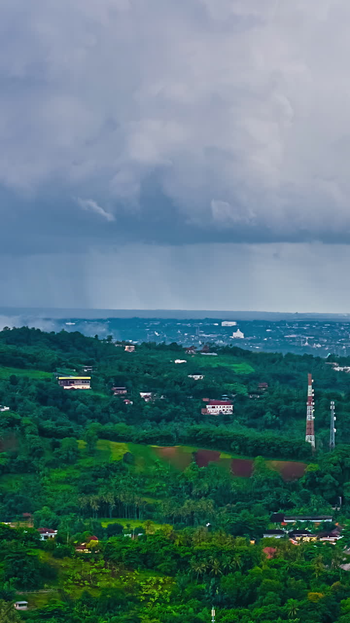 Thick clouds release rain over lush Balinese hills and rural villages, drone hyperlapse