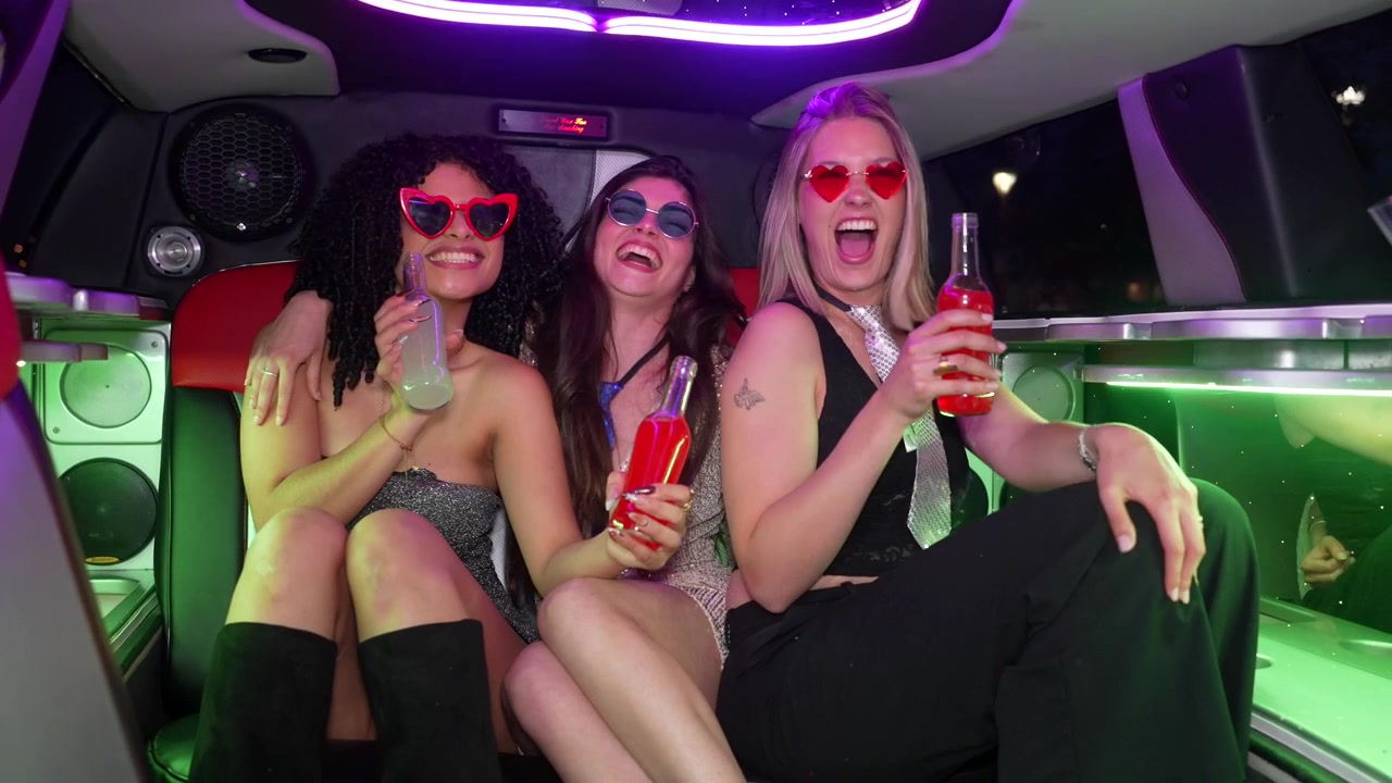 Glada unga kvinnor skrattar och firar i en limousine