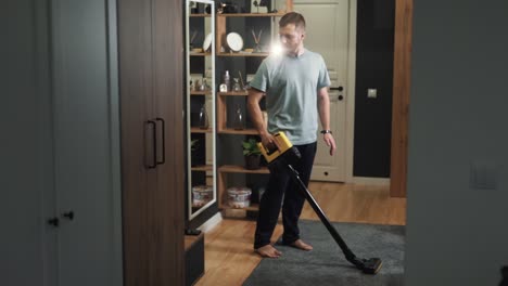 a young man thoroughly cleans the house with a cordless vacuum cleaner