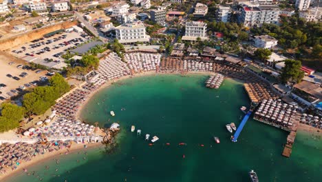 ksamil, albania, con playas llenas de gente, turistas nadando y barcos atracados cerca, vista aérea