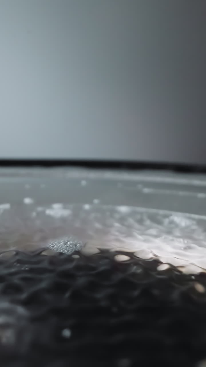Loud speaker plays music with diaphragm covered with water. Diaphragm moves creating sound. Waves form on water from movement of device elements macro