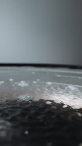 loud speaker plays music with diaphragm covered with water. diaphragm moves creating sound. waves form on water from movement of device elements macro