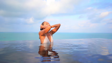 Sexy-Asian-Woman-Relaxing-in-Swimming-Pool,-Seascape-Background-SLOMO