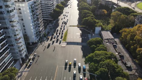 Aerial-flyover-avenue-with-traffic-in-Buenos-Aires-during-sunny-day-surrounded-by-green-trees-and-skyscraper-buildings