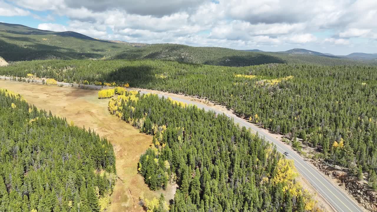 Colorado mountain road with aspens and pines and fluffy clouds
