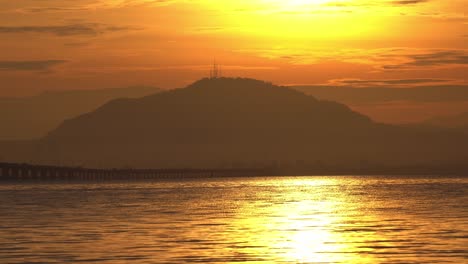 silhouette morning sunrise of car move at the penang bridge across the sea.