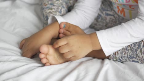 niño pequeño jugando con los pies en la cama