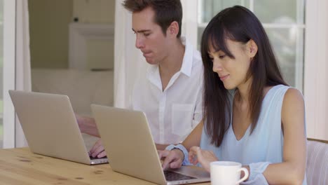 una pareja joven y tranquila sentada en la mesa usando una laptop