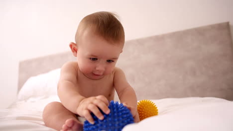 bebé jugando con bolas de masaje en la cama