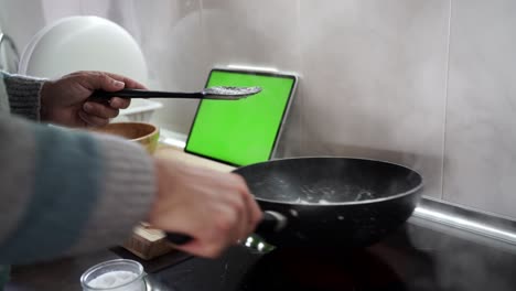 Over-the-shoulder-shot-of-a-man-cooking-sepia-using-a-recipe-from-his-tablet