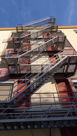 nubes que pasan sobre un edificio industrial fresco, con escalera de metal exterior en vertical