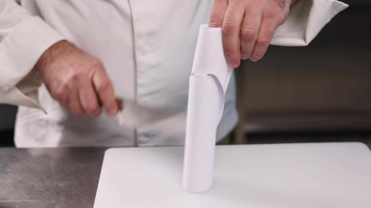 chef demostrando cómo cortar papel envuelto con un cuchillo