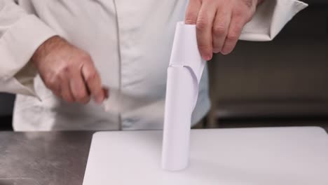 chef demonstrating how to cut wrapped paper with a knife