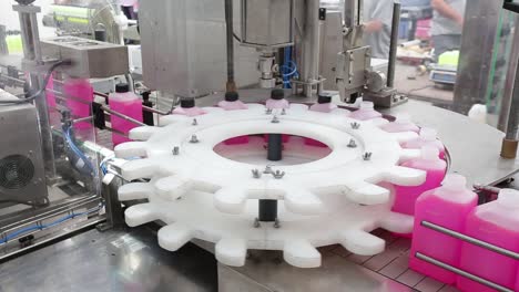 overview of a bottle capping machine during a filling up process on an automatic industrial line
