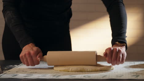 pastry chef flattening the cinnamon roll dough with a rolling pin. - closeup shot