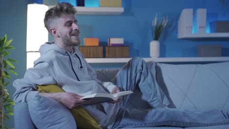 el hombre está leyendo un libro en el sofá.