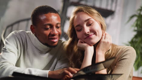 black bearded man with beloved white woman looks at pictures