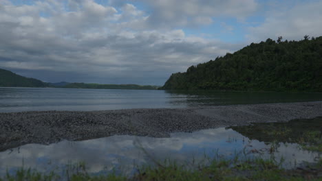 Weitwinkelaufnahme-Des-Rotoma-Sees-Mit-Wolken,-Die-Sich-Im-Wasser-Spiegeln