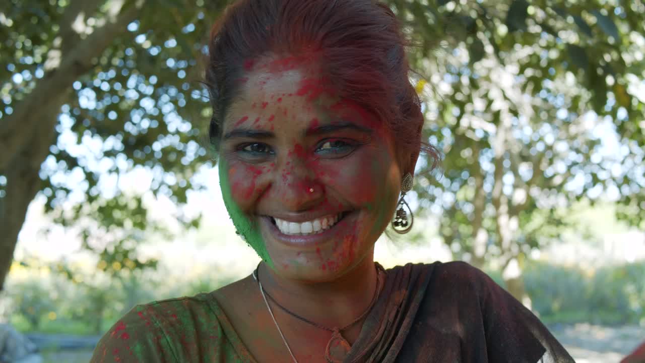 인도 여성의 가까운 얼굴은 밝은 홀리 색으로 얼룩져 있습니다.