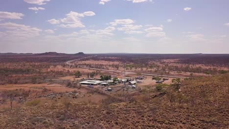 aerial view of rest stop by stuart highway in rural south australia, desert landscape and traffic, wide drone shot