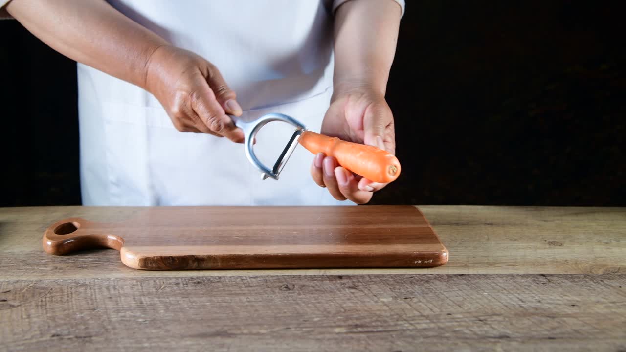 las manos de la mujer pelan zanahorias frescas