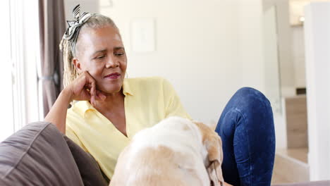 a senior african american woman with grey hair is relaxing with her dog