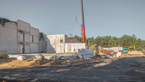 Schatten-Bewegen-Sich,-Während-Die-Sonne-Den-Himmel-über-Einer-Baustelle-Durchquert---Kran,-Der-Einen-Schiffscontainer-Justiert---Zeitraffer