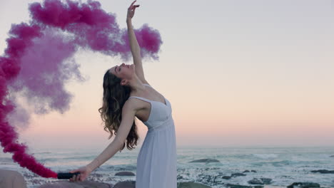 Mujer-Sosteniendo-Una-Bomba-De-Humo-Rosa-Bailando-En-La-Playa-Temprano-En-La-Mañana-Celebrando-La-Libertad-Creativa