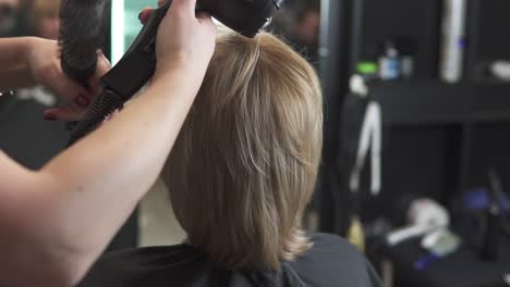 professioneller friseur mit einem fön nach dem haarschnitt