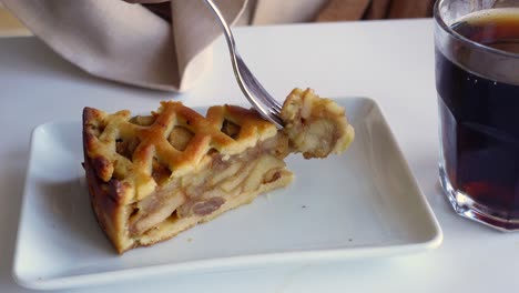 una rebanada de pastel de manzana con un tenedor y un vaso de café