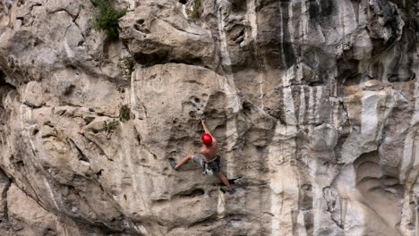 male rock climber ascending a chinese karst mountain rock face, aerial view