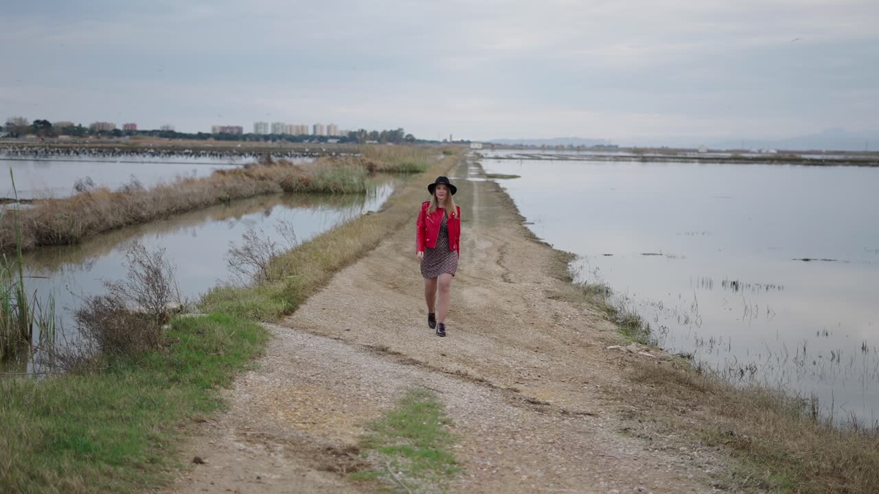 Woman Walking on a Country Road by a Waterway