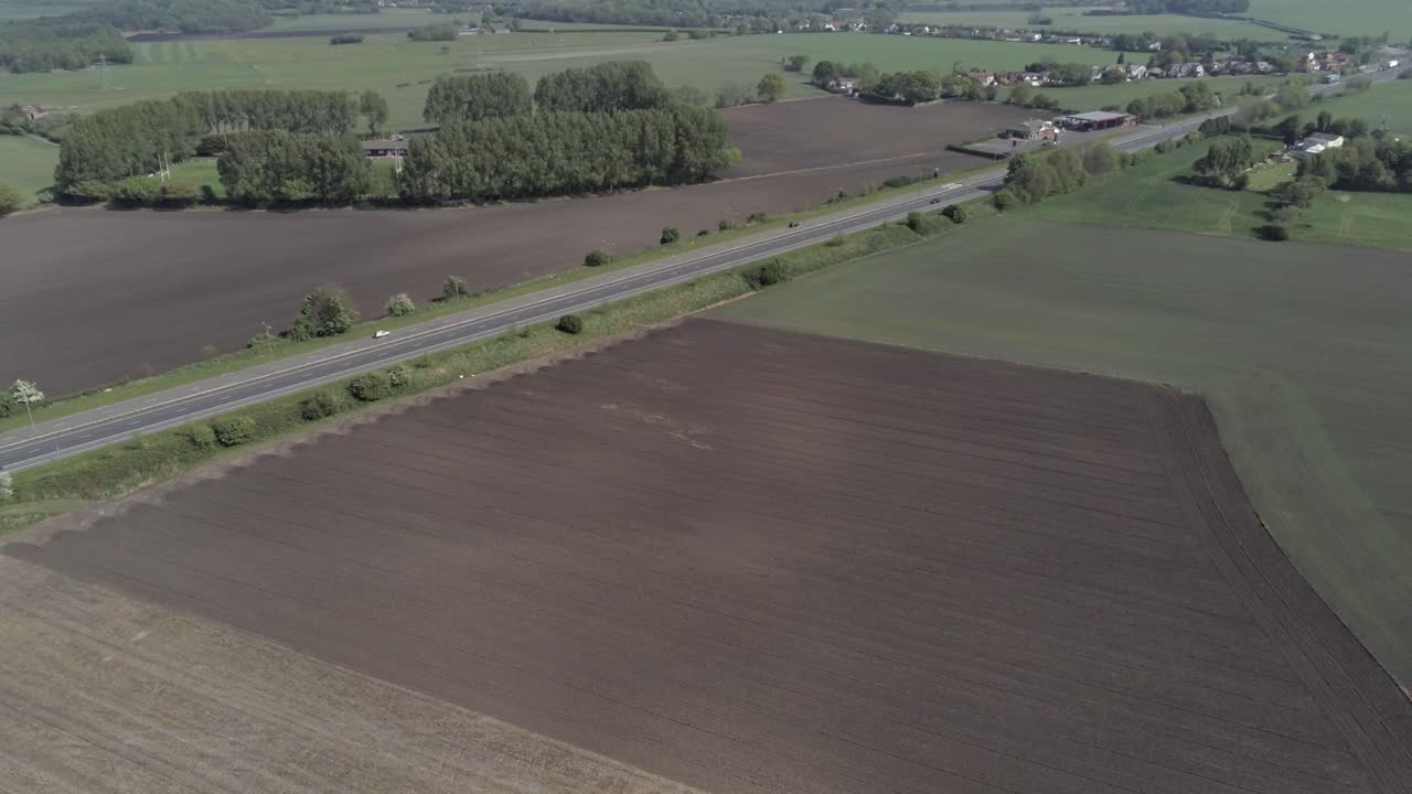 Drone aerial view above British A580 East Lancs highway in rural agricultural countryside wide orbit left