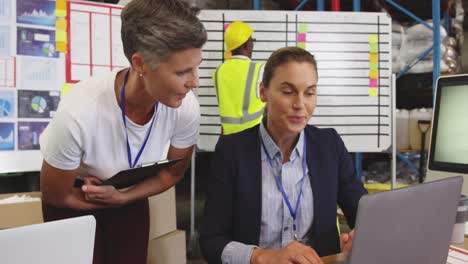 Two-woman-talking-at-a-desk-in-a-warehouse-4k