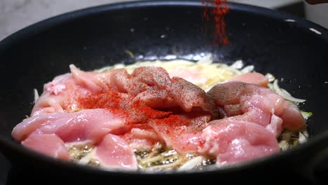 cooking chicken with red pepper and black pepper in a pan