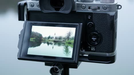 primer plano de la parte posterior de la cámara digital vintage fotografiando una imagen de reflejo perfecta en un lago y una iglesia en eslovenia