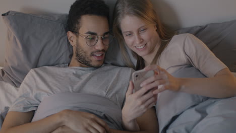 pareja viendo el teléfono en la cama