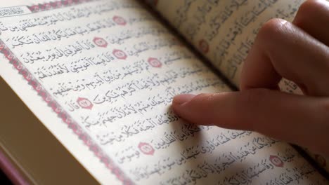 close up shot of a quran and a female person tracing the verses in the quran with her finger