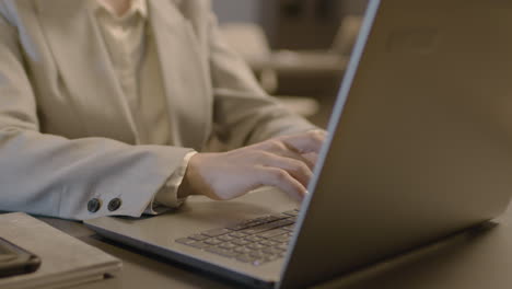 close up of employee woman hands typing on laptop keyboard at workplace