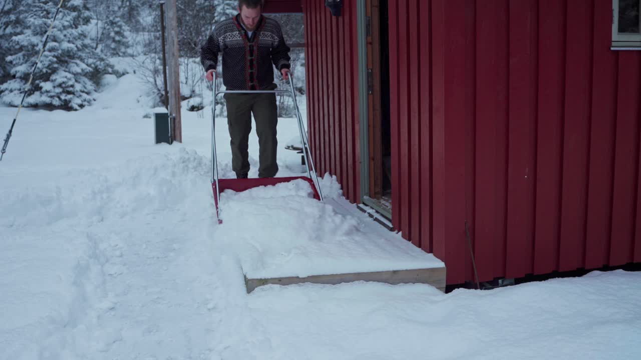 un hombre guapo con ropa de invierno limpiando la nieve con una pala de trineo en la puerta y la mantuvo dentro