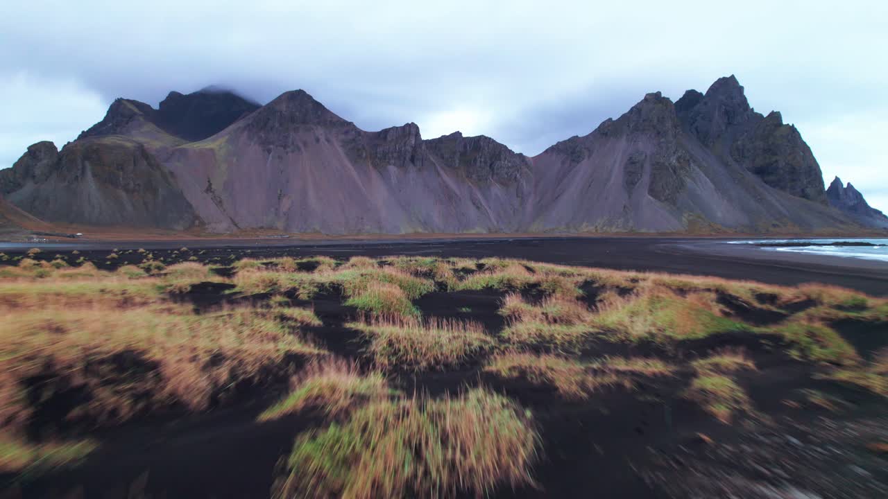 desde el aire: el sobrevuelo vestrahorn, con sus icónicos picos dentados y imponentes contrafuertes, se eleva dramáticamente desde esta oscura extensión como una colosal catedral de piedra