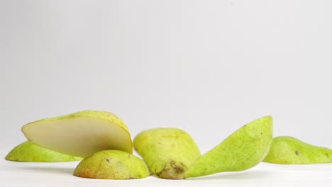 pear slices falling and bouncing on white studio backdrop in 4k slow motion