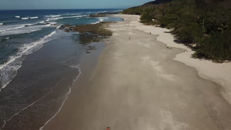 imágenes de drones sobre una playa tropical, gente caminando por la arena, santa teresa, costa rica