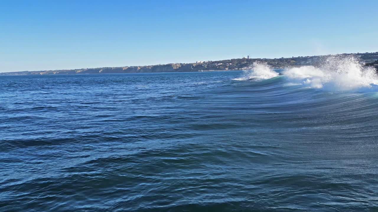 tiro de drone que muestra el horizonte de la ola rompiendo en las rocas mientras los leones marinos saltan del agua durante la marea real en la jolla, california