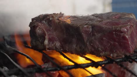 primer plano de filete a la parrilla entre llamas y brasas de carbón de barbacoa